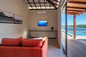 a living room with a red couch and a television at Casa Pé no Lago - Descanso em Família na Praia de Barra Grande! in Barra Grande