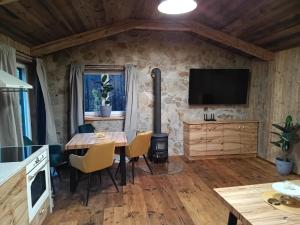 a dining room with a table and a tv on a stone wall at WoodhouseOld in Červená Voda