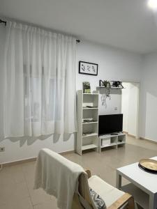 a living room with white curtains and a tv at Casa 22 in Plasencia