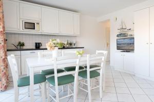 a white kitchen with a white table and chairs at Seepferdchen Freetied in Sierksdorf +30 photos