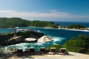 un balcón con sillas, sombrillas y el océano en Casas del Acantilado - Acapulco, en Acapulco