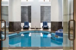 a pool in a hotel lobby with two blue chairs at Le Méridien Mexico City Reforma in Mexico City