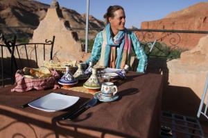 a man sitting at a table with teapees on it at KASBAH DES MONTAGNS maisons d'hôtes la vallée des roses in Bou Drarar