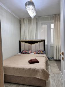 a bedroom with a large bed with a chandelier at Квартира по суточно in Aktau