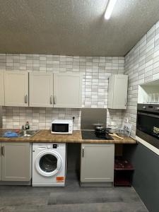 a kitchen with a washing machine and a microwave at Room 1 in south Yorkshire in Sheffield