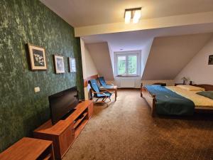 a hotel room with a bed and a tv and a bed and a couch at Pensjonat Leśny Dworek SPA & Garden Uzdrowisko wśród Natury in Cisów