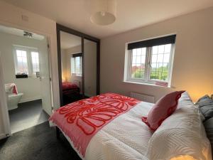 Down HatherleyにあるKale Drive House Long Stays Welcome Free Parking, Sleeps 6のベッドルーム1室(ベッド1台、赤と白の掛け布団付)