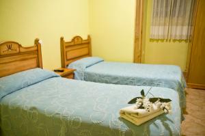 クエンカにあるPensión Aries IIのベッドルーム1室(ベッド2台、青いシーツ、タオル付)