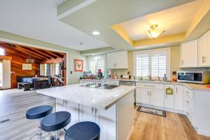a kitchen with white cabinets and a large island with stools at 9 Mi to Spanaway Park Home with Indoor Hot Tub in Graham