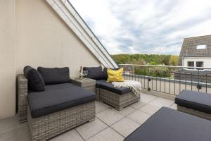 a balcony with wicker chairs and a yellow pillow at Baltic Sea Lodge Küstenidyll in Scharbeutz