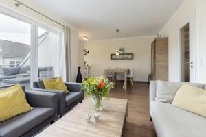 a living room with couches and a vase of flowers on a table at Baltic Sea Lodge Küstenidyll in Scharbeutz