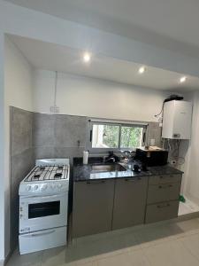 a kitchen with a white stove and a sink at Dpto Villa María - Excelente Estadía in Villa María