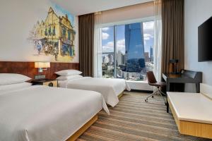 ein Hotelzimmer mit zwei Betten, einem Schreibtisch und einem Fenster in der Unterkunft Four Points by Sheraton Kuala Lumpur, Chinatown in Kuala Lumpur
