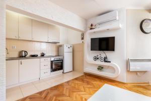 a kitchen with white cabinets and a flat screen tv at Apartment Dar & Mar in Herceg-Novi