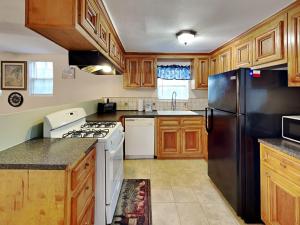 Una cocina con gabinetes de madera y un refrigerador negro. en Sugar Shack Bungalow, en Galveston