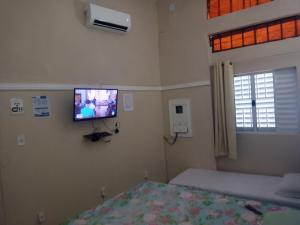 una camera da letto con un letto e una TV a parete di Casa de hospedagem a Aparecida