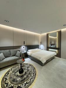 a bedroom with a bed and a couch and a table at استديو فاخر بجلسه ودخول ذاتي in Al Hofuf