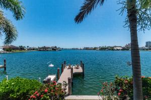 a dock on a lake with a palm tree at Southern Exposure I Waterfront 5 Bed House I Wide Water Views of Landmark Bay in Marco Island +33 photos