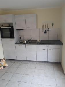 AlbertsdorfにあるAn der alten Pappel Nr 3のタイルフロアのキッチン(白いキャビネット付)