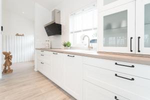 a white kitchen with white cabinets and a sink at Ahoi Lee in Blekendorf
