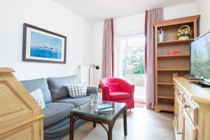 een woonkamer met een blauwe bank en een rode stoel bij Ferienhaus am Strandwäldchen in Timmendorfer Strand