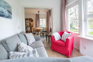 een woonkamer met een bank en een rode stoel bij Ferienhaus am Strandwäldchen in Timmendorfer Strand