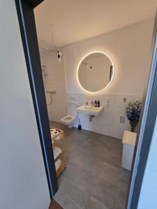 a bathroom with a sink and a toilet and a mirror at Stilvolle Neubauwohnung mit Balkon&WLAN in Hannover