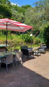a patio with tables and chairs and a red umbrella at Casa Vacanze VERDE MARE RELAX in La Spezia