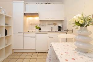 a kitchen with white cabinets and a table with a vase at Erlenstübchen in Scharbeutz