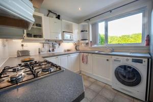 a kitchen with a stove and a washing machine at Beautiful attractive house free parking near Airport in Edinburgh