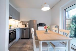 a kitchen with a wooden table with chairs and a table and a kitchen with at Alte Bergstraße 6 Sehnsucht in Scharbeutz +21 photos