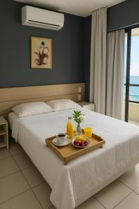 a hotel room with a tray of food on a bed at Flat Vista Mar com Piscina e Wi-Fi Rápido Rio Vermelho in Salvador