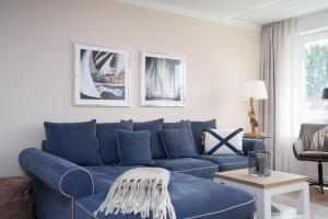 a living room with a blue couch and a table at Hauptstraße 26e Deck 9 in Timmendorfer Strand