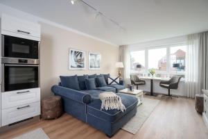 a living room with a blue couch and a tv at Hauptstraße 26e Deck 9 in Timmendorfer Strand +24 photos