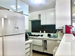 a kitchen with white cabinets and a white refrigerator at Condomínio Natture Clube in Natal +1 photo