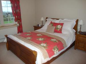 a bed with a red and white blanket and a window at The Paddock in Haverfordwest