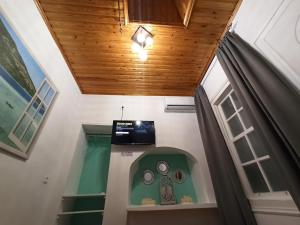 a room with a ceiling with a window and a television at Little Angelo's Cottage - Greek Summer Escape in Plomari