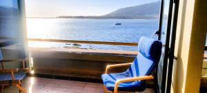 a blue chair sitting in a window looking out at the water at Casa Foz do Rio in Caminha