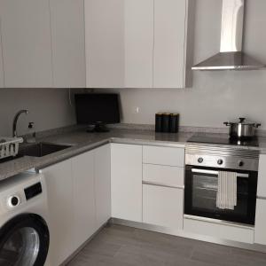 a kitchen with white cabinets and a sink and a stove at Burrianna Beach Apartment in Burriana