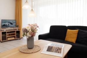 a living room with a vase of flowers on a table at Schützenweg 6 Ostseesonne in Kellenhusen +31 photos