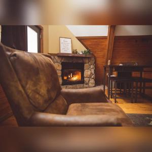 a leather couch in a living room with a fireplace at A-Frame #03 - by The Chalets in Logan +13 photos