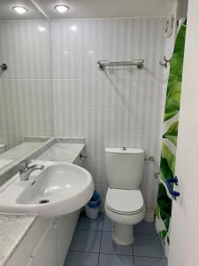 a white bathroom with a toilet and a sink at San Alfonso del Mar Faro 702 in Algarrobo