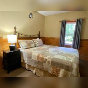 a bedroom with a bed with a lamp and a window at A-Frame #12 - by The Chalets in Logan