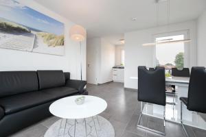 a living room with a black couch and a white table at Brenkenhagener Weg 4 Wohnung 7 in Grömitz
