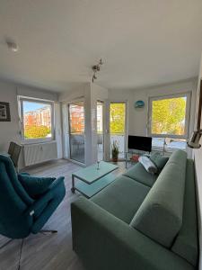 a living room with a green couch and a table at Duhner Leuchturm, Ferienwohnung DL02 in Cuxhaven