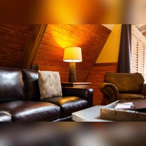 a living room with leather furniture and a lamp at A-Frame #15 - by The Chalets in Logan