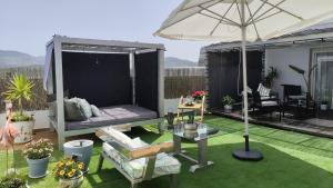 a screened in porch with an umbrella on a lawn at ÁTICO RILQUE, Apartamentos Independientes con Jacuzzi Privado y Terraza en Ronda in Ronda