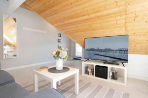 ein Wohnzimmer mit einem großen TV und einem Tisch in der Unterkunft Appartementhausanlage Tiemann Bernstein in Kellenhusen