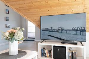 einen Flachbild-TV auf einem weißen Stand im Wohnzimmer in der Unterkunft Appartementhausanlage Tiemann Bernstein in Kellenhusen