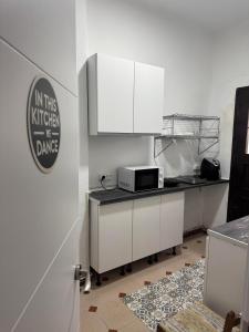 una cucina con mobili bianchi e un forno a microonde di Hostal El Torero ad Alcalá de Henares
